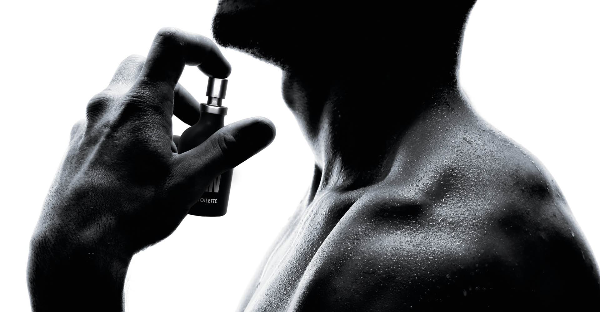 immagine di un uomo, in cui si vedono solo le spalle viste di lato che si sta spruzzando il profumo nel collo